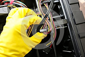 Inside details of the personal computer. Man is cleaning wires in yellow gloves. Motherboard and video card in the dust. Broken PC