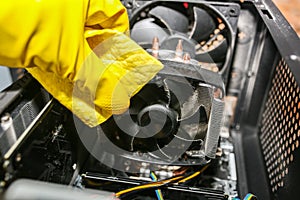 Inside details of the personal computer. Man is cleaning wires in yellow gloves. Motherboard and video card in the dust. Broken PC