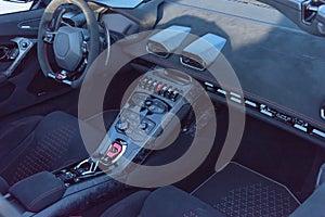 Inside driver seat of super car with steering wheel and modern features on dashboard