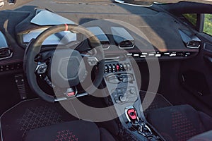 Inside driver seat of super car with steering wheel and modern features on dashboard