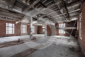 Inside an empty spacious dirty old abandoned industrial building with peeling paint and floor tiles coming up