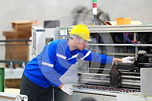 Inside a factory, industrial worker in action on machine.