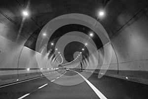 Inside a highway tunnel, a car turning left in black and white.