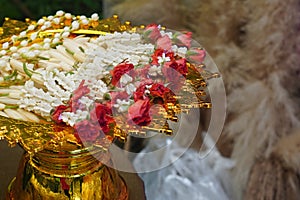 inside left, white and red garland is placed on a golden pedestal on blur background, nature, object, worship, buddha, copy space