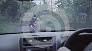 Inside of moving car in rural road with bike and truck riding in front of it.