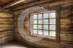 Inside of an old log home facing windows.