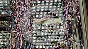 Inside a PABX telephone booth that has a number of connecting cables in many colors in the analog