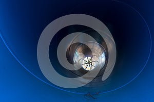 Inside perspective of big blue water pipe used as water tunnel in irrigation project.