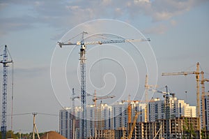 Inside place for many tall buildings under construction and cranes under a blue sky working on place with tall homes