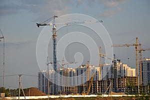 Inside place for many tall buildings under construction and cranes under a blue sky working on place with tall homes