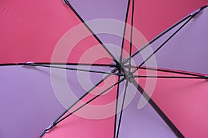 Inside shot of open colorful umbrella with black metal spoke and pole