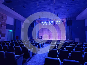 Inside shot of a small empty auditorium with four microphones on the stage