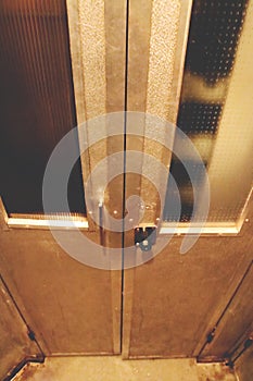 The inside of a small old elevator.