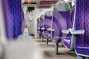 Inside the train wagon. Empty comfortable and colorful chairs in a modern electric train.