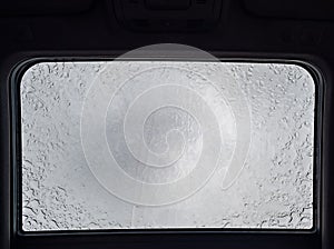 Inside a vehicle looking up to a sunroof with water droplets