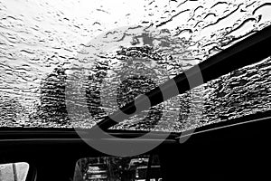 Inside a vehicle looking up to a sunroof with water droplets