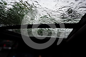 Inside a vehicle looking up to a sunroof with water droplets