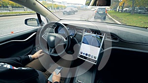 Inside view of an automobile which is driving by itself and a man sitting in it