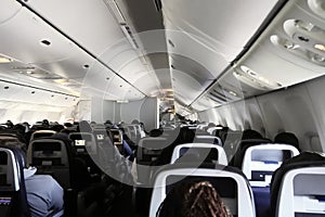 Inside view of large commercial airliner aisle with diverse passengers