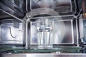 Inside view of new clean staniless, microwave oven with a cup of pure water photo