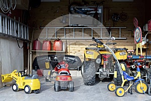 Inside view open door ATV quad bike motorcycle parking messy garage,clutter stuff, children toys and bicylce storage