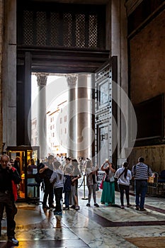 Inside view of people next to the big entrance door at the famous Pantheon building in Rome.