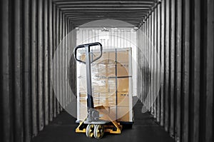 Inside view of shipping container. Cargo shipment boxes stacked on pallet with hand pallet truck. Industry cargo freight transport