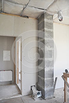 An inside view on unfinished house construction with a chimney liner inserted into a soapstone flue liner, ventilation pipes,