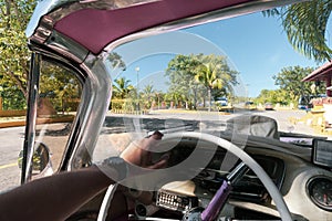 Inside of a vintage pink classic american car in Cuba. driver holds the steering wheel of old car with his hand. Varadero