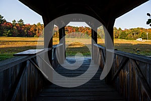 Inside vintage wood covered bridge. surrounded by colorful autumn leaves forest background. Old wooden building architecture.