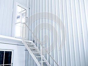 Inside white modern cutting-edge shipping container construction office building with white iron staircase leads up to the glass.