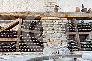 Inside a wine cellar with aged dust bottles and rustic wooden shelves. Historical storage of winery