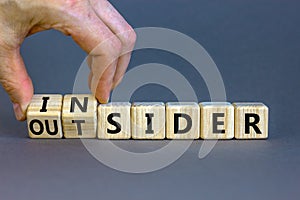 Insider or outsider symbol. Businessman turns a cube, changes the word insider to outsider. Beautiful grey table, grey background