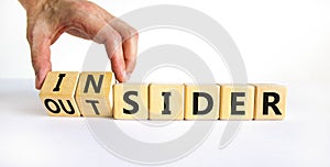 Insider or outsider symbol. Businessman turns a cube, changes the word insider to outsider. Beautiful white table, white