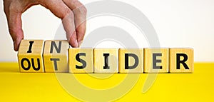 Insider or outsider symbol. Businessman turns a cube, changes the word insider to outsider. Beautiful yellow table, white