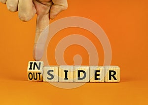 Insider or outsider symbol. Businessman turns wooden cubes and changes the concept word Insider to Outsider. Beautiful orange