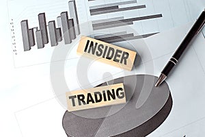 INSIDER TRADING wooden block on chart background