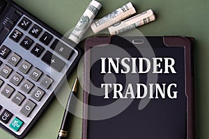 INSIDER TRADING - words in an electronic notebook on the background of a calculator and banknotes