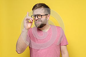 Insidious bearded Caucasian man in glasses and a pink t-shirt had an idea, he raised finger up and looked slyly.