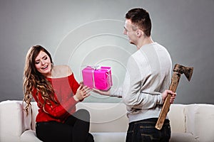 Insincire man holding axe giving gift box to woman