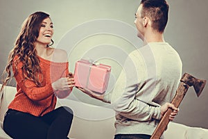 Insincire man holding axe giving gift box to woman