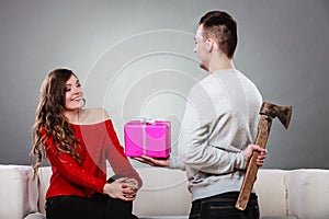 Insincire man holding axe giving gift box to woman