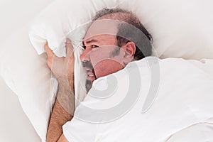 Insomniac clutching at his pillow in desperation photo