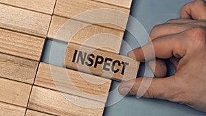 INSPECT word concept. Close-up wooden piece blocks on the table