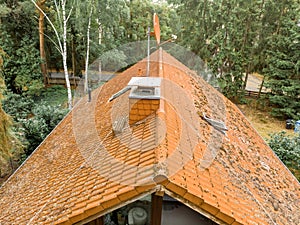 Inspection of the red tiled roof of a detached house, with a covered chimney and a satellite antenna.
