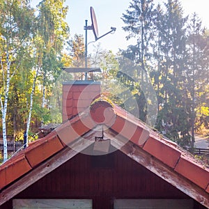 Inspection of the red tiled roof of a detached house, with a covered chimney and a satellite antenna..