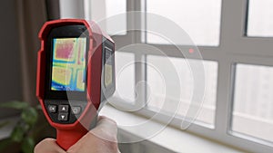 Inspection of a window block inside the room with a thermal imager, searching for heat loss in a building. Thermography