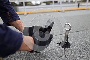 Inspector auditor technician using his phone photographing fall arrest, fall restraint roof anchor point photo