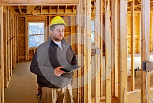 Inspector checking building during house construction on tablet PC with hard hat