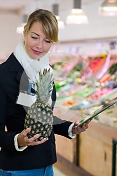 inspector checking pineapple in green grocers